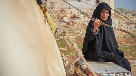 Eine Frau neben einer provisorischen Unterkunft.