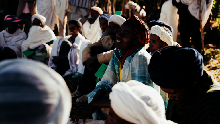Frauen und Männer sitzen während eines Workshops auf dem Boden und hören zu.