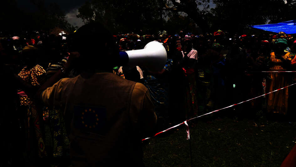 A man with a megaphone addresses a group of people