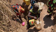 2021-duerre-kenia-frauen-holen-wasser-am-fluss.jpg Women draw water from a muddy hole.
