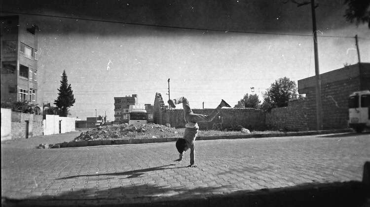 2017-fotoprojekt-handstand-tuerkei-syrien-ziyad-2.jpg A child doing a handstand in front of rubble