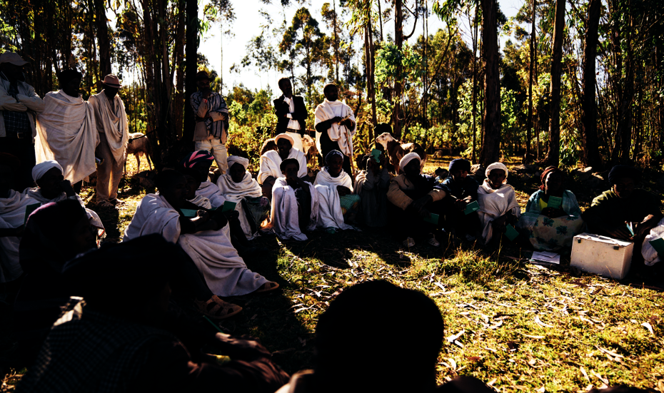 Frauen und Männer sitzen in einem Kreis. Einige lächeln.