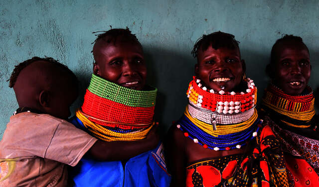 Kenyan women wearing traditional clothing smile towards the camera