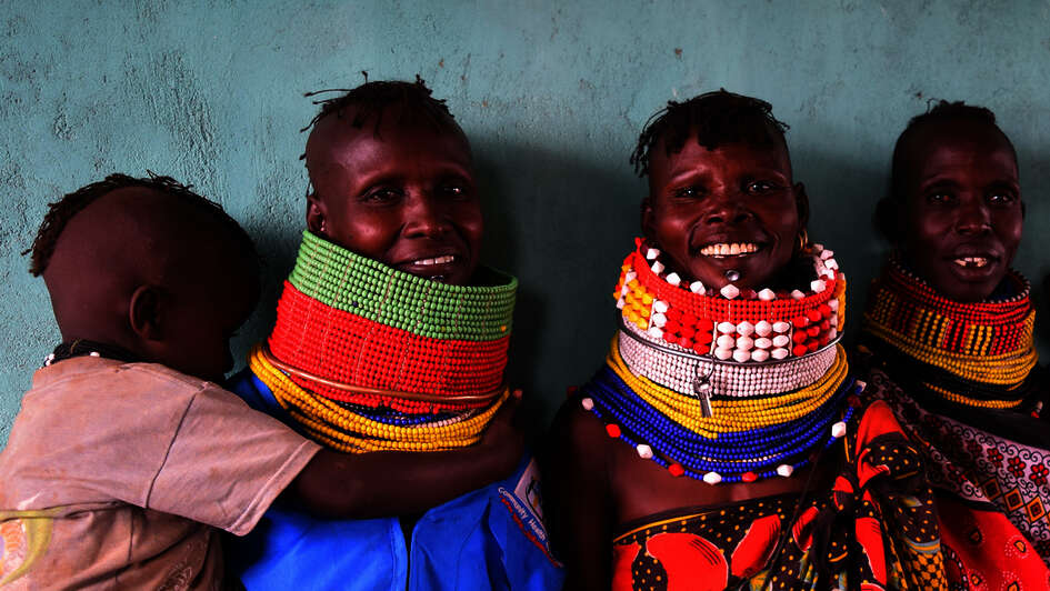 Kenyan women wearing traditional clothing smile towards the camera