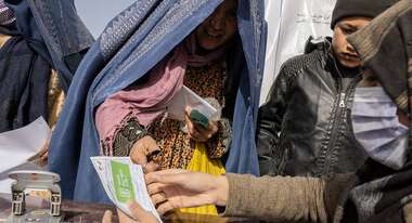 Eine Frau lächelt und nimmt ein Registrierungsausweis entgegen.