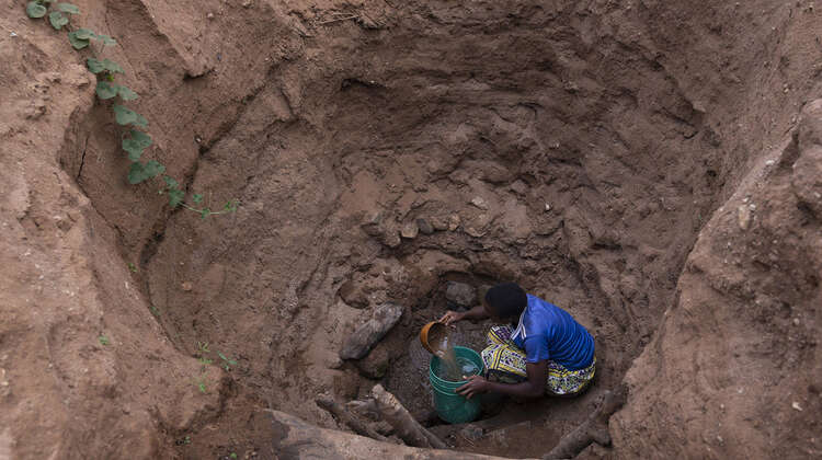 2021-kenia-kinakoni-ausgetrocknetes-flussbett-brunnen-40-millionen-vor-hungersnot.jpg Eine Frau holt Wasser aus einem tiefen Loch in einem ausgetrockneten Fluss, Kenia 2021.