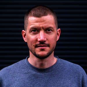 Porträtbild von Stefan Isbrecht. Er hat kurze Haare und trägt einen grauen Pullover.