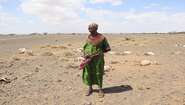 2022-frau-totes-vieh-duerre-marsabit-kenia-c-asenath-niva.jpg Dürre in Kenia: Eine Frau steht auf einem Feld, im Hintergrund sieht man totes Vieh.