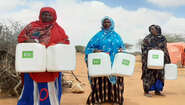 2022-duerre-frauen-wasserbehaelter-somalia-c-welthungerhilfe.jpg Drei Frauen stehen nebeneinander, sie halten alle zwei Wasserbehälter mit Welthungerhilfe-Logo.