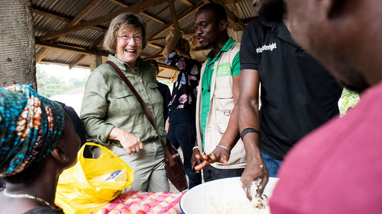 2019-marlehn-thieme-sierra-leone-schaukochen-lann_C_kai-loeffelbein.jpg Women and men are laughing together. There's food on the table.